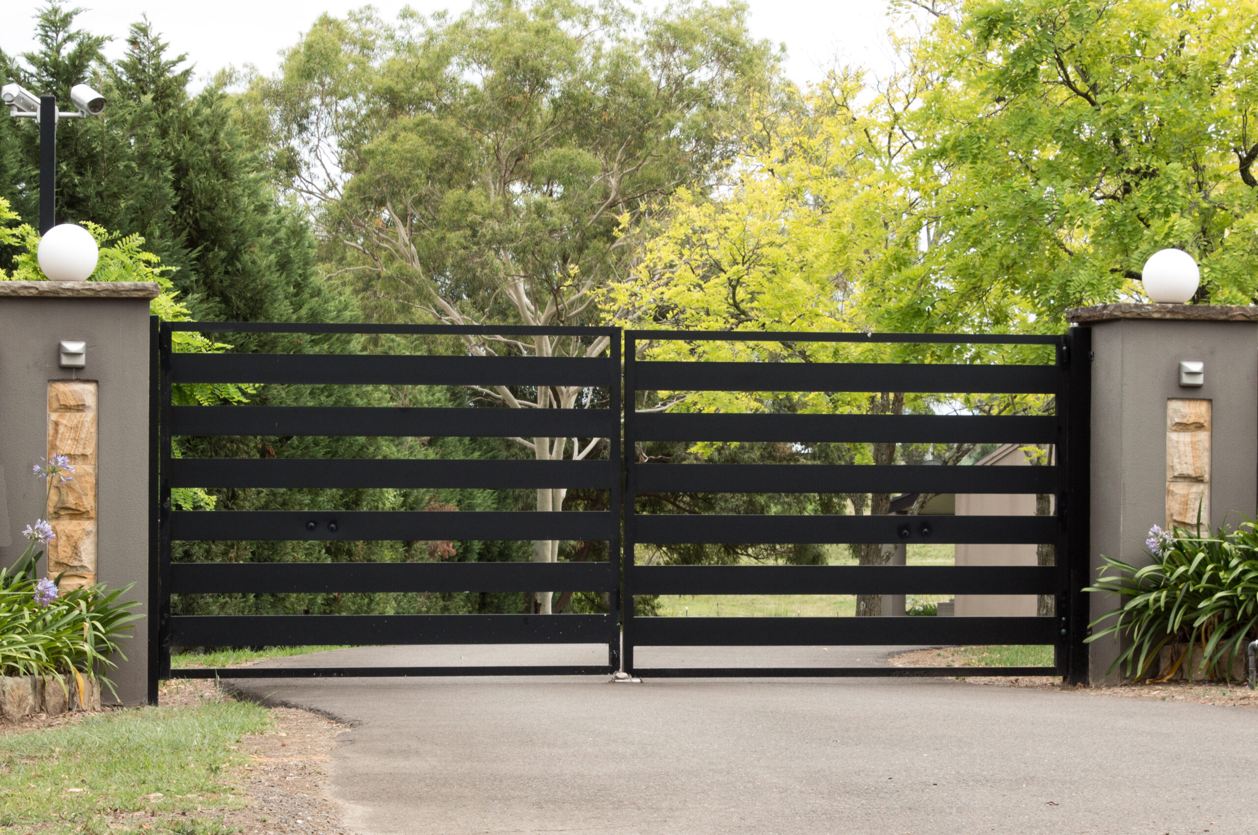 Black metal driveway entrance gates set in brick fence