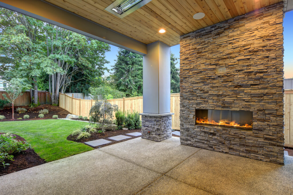 Outside Patio features natural wood plank ceiling, concrete floor and oversized stone fireplace overlooking a beautiful expansive yard.  Northwest, USA